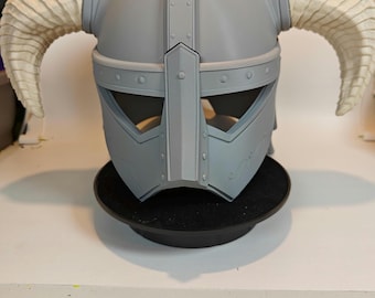 May include: A gray helmet with curved, off-white horns. The helmet has a visor with eye openings and decorative rivets. The design is reminiscent of a Viking or fantasy warrior helmet, suitable for cosplay or display.