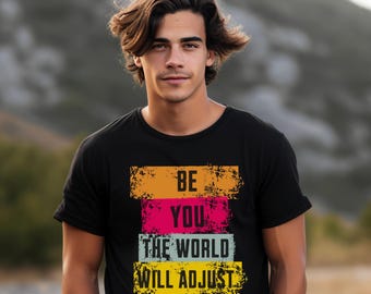 May include: Black t-shirt with the text "BE YOU THE WORLD WILL ADJUST" in orange, pink, blue, and yellow. The text is in a distressed, textured style. The shirt has rolled-up sleeves.