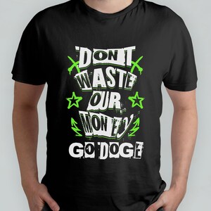 May include: Black t-shirt with a white graphic that says "Don't waste our money, Go Doge!" in a stylized font. The graphic also includes green lightning bolts, stars, and crossed pickaxes.