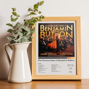 Könnte beinhalten: Ein gerahmtes Poster für das Musical "Der seltsame Fall des Benjamin Button". Das Poster zeigt ein tanzendes Paar mit Text, der den Titel, die Besetzung und die Titelliste enthält. Links befindet sich ein weißer Krug mit grünem Laub.