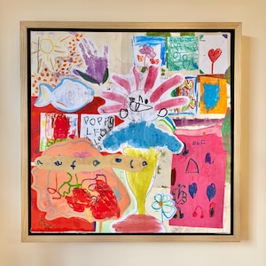 May include: A framed collage of children's drawings featuring a central figure with pink hair, a blue torso, and a yellow base. The artwork includes various colorful sketches of a sun, a purple handprint, a fish, hearts, and flowers on a light background.