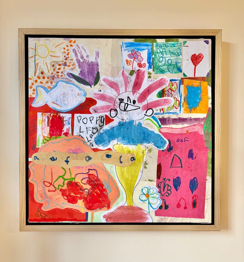 May include: A framed collage of children's drawings featuring a central figure with pink hair, a blue torso, and a yellow base. The artwork includes various colorful sketches of a sun, a purple handprint, a fish, hearts, and flowers on a light background.