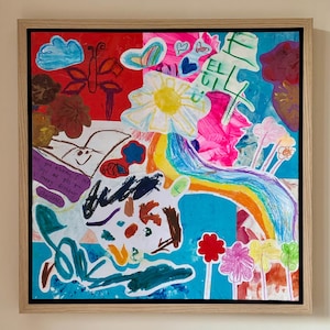 May include: A framed mixed-media artwork featuring a vibrant collage of children's drawings and paintings. The composition includes a rainbow, a yellow sun, flowers, a butterfly, and clouds in various colors. Handwritten text reads: Love you mommy. I love you and give you my happy birthday. Charlotte.