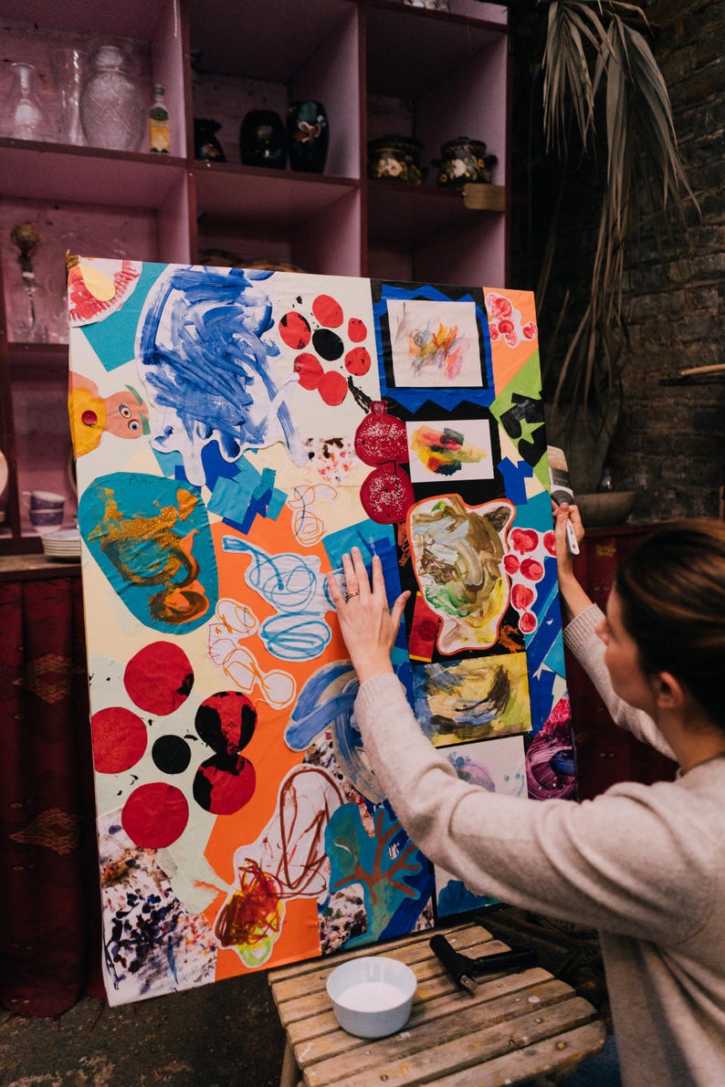 May include: A large rectangular canvas featuring a vibrant collage of abstract shapes, painted textures, and layered paper cutouts in bright shades of blue, orange, red, and green. The artwork displays various hand-drawn scribbles and patterns.