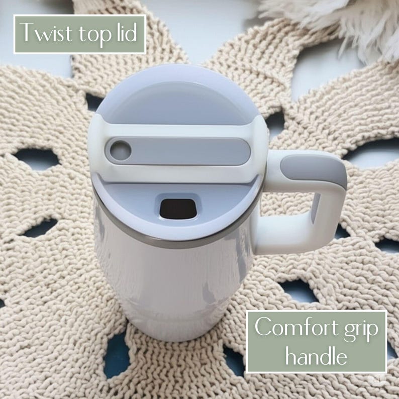 May include: A white tumbler with a gray and white twist top lid and a comfort grip handle. The lid features a rectangular gray accent and a small drinking opening. The tumbler has a smooth, cylindrical body and a sturdy side handle.