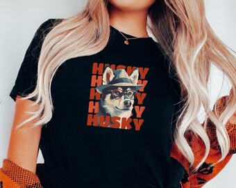 May include: Black t-shirt with a graphic of a husky dog wearing a hat and sunglasses. The text "HUSKY" is repeated in red letters.
