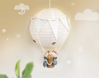 Pantalla de globo aerostático en gris suave y blanco con cesta de mimbre natural o arpillera hecha a mano para habitación infantil, guardería o sala de juegos.