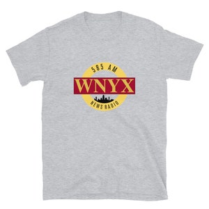 May include: A grey t-shirt with a yellow and red circular logo that says "585 AM WNYX NEWS RADIO" with a silhouette of a city skyline inside the circle.