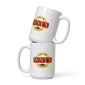 May include: Two white ceramic mugs stacked on top of each other. Both mugs feature a yellow circle with a red band and the text "585 AM WNYX NEWS RADIO" in black and gold lettering.
