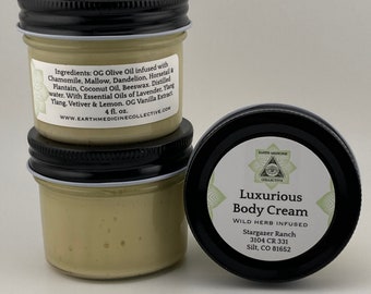 May include: Two glass jars of luxurious body cream with a black lid. The jar on the right has a label that reads "Luxurious Body Cream Wild Herb Infused Stargazer Ranch 3104 CR 331 Silt, CO 81652". The jar on the left has a label that reads "Ingredients: OG Olive Oil infused with Chamomile, Mallow, Dandelion, Horsetail & Plantain, Coconut Oil, Beeswax. Distilled water. With Essential Oils of Lavender. Ylang Ylang, Vetiver & Lemon. OG Vanilla Extract. 4 fl. oz. WWW.EARTHMEDICINECOLLECTIVE.COM"