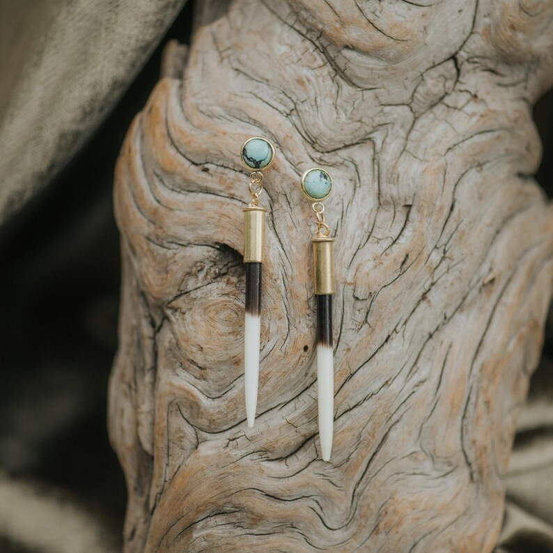 May include: A pair of long, gold earrings with a turquoise stone at the top and a black and white bone-like pendant.