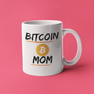 May include: White ceramic mug with a black and gold design. The mug says "Bitcoin Mom" with a Bitcoin symbol.
