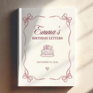 May include: A white hardback book with red line art featuring a decorative ribbon border, a birthday cake illustration, and the text "Emma's BIRTHDAY LETTERS" followed by "SEPTEMBER 03, 2026" and a small heart symbol centred on the front cover.