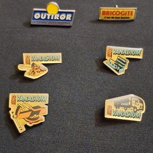 Peut inclure: Collection de badges métalliques vintage avec divers motifs et textes. Les badges présentent les mots "OUTIROR", "BRICOGITE" et "VANADIUM" avec des graphiques. Les badges sont dans des tons de jaune, bleu et argent.