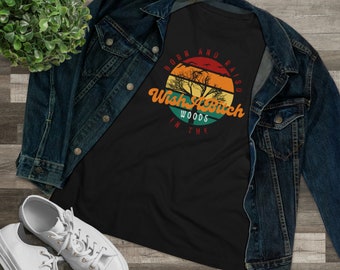 Könnte beinhalten: Schwarzes T-Shirt mit einem farbenfrohen Grafikdesign mit Sonnenuntergang, Bäumen und dem Text "Born and Raised Wish a Witch in the Woods". Das Shirt wird mit einer Jeansjacke und weißen Turnschuhen kombiniert.