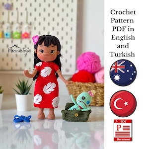 Puede incluir: Una muñeca de ganchillo hecha a mano con un vestido rojo con diseños de hojas blancas, una flor rosa y cabello negro. Una muñeca verde más pequeña está en un recipiente de ganchillo verde. La imagen incluye texto: Crochet Pattern PDF in English and Turkish.