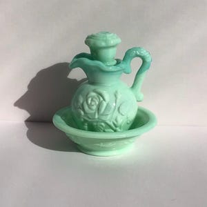 K&ouml;nnte beinhalten: Ein Vintage-Set aus hellgr&uuml;ner Glaskanne und Sch&uuml;ssel. Die Kanne hat ein Rosendesign und einen Griff. Die Sch&uuml;ssel ist rund mit einem passenden Rosenmuster. Das Set ist wahrscheinlich f&uuml;r dekorative Zwecke gedacht.
