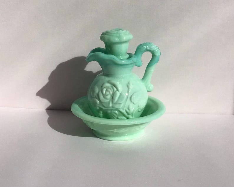 K&ouml;nnte beinhalten: Ein Vintage-Set aus hellgr&uuml;ner Glaskanne und Sch&uuml;ssel. Die Kanne hat ein Rosendesign und einen Griff. Die Sch&uuml;ssel ist rund mit einem passenden Rosenmuster. Das Set ist wahrscheinlich f&uuml;r dekorative Zwecke gedacht.