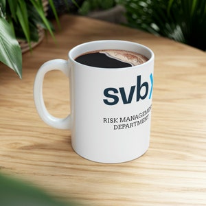 May include: White coffee mug with a black and blue logo that says "svb" and "RISK MANAGEMENT DEPARTMENT".