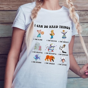 May include: White t-shirt with the text "I can do hard things" and illustrations of animals with positive affirmations, such as "I am kind", "I am brave", "I am smart", "I am helpful", "I am grateful", "I am enough", "I am strong", "I am unique", and "I am loved".