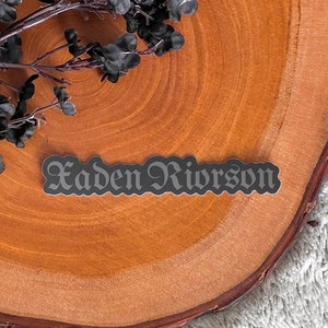 May include: A black and white sticker with the name "Kaden Rivorson" written in a gothic font.