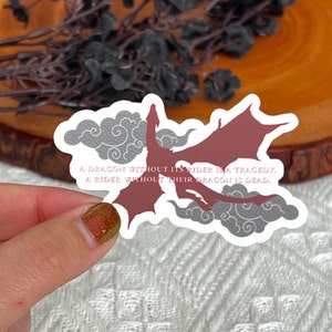May include: A sticker with a red dragon silhouette flying through gray clouds. The text reads "A dragon without its rider is a tragedy. A rider without their dragon is dead."