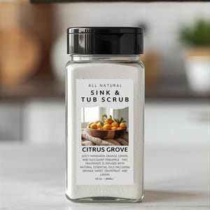 May include: A clear glass jar with a black lid, labeled "ALL NATURAL SINK & TUB SCRUB." The label features text "CITRUS GROVE" and a graphic of oranges. The jar contains a white powder and is 16 oz (454g).