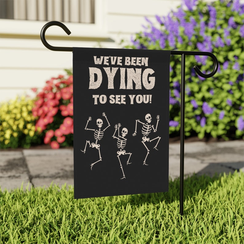 May include: Black Halloween garden flag with three white skeletons dancing and the text "We've been DYING to see you!"
