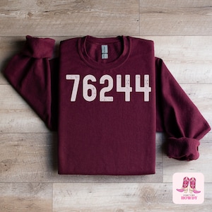 May include: Burgundy sweatshirt with the number 76244 printed in white on the front.