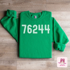 May include: Green sweatshirt with the number 76244 printed in white on the front.