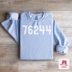 May include: Light blue sweatshirt with the number 76244 printed in white on the front.