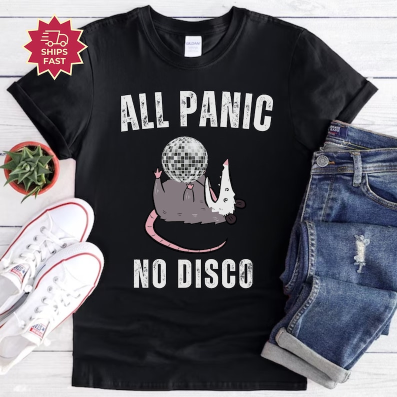 May include: Black t-shirt with a white graphic of a possum holding a disco ball. The text "All Panic No Disco" is printed below the possum.