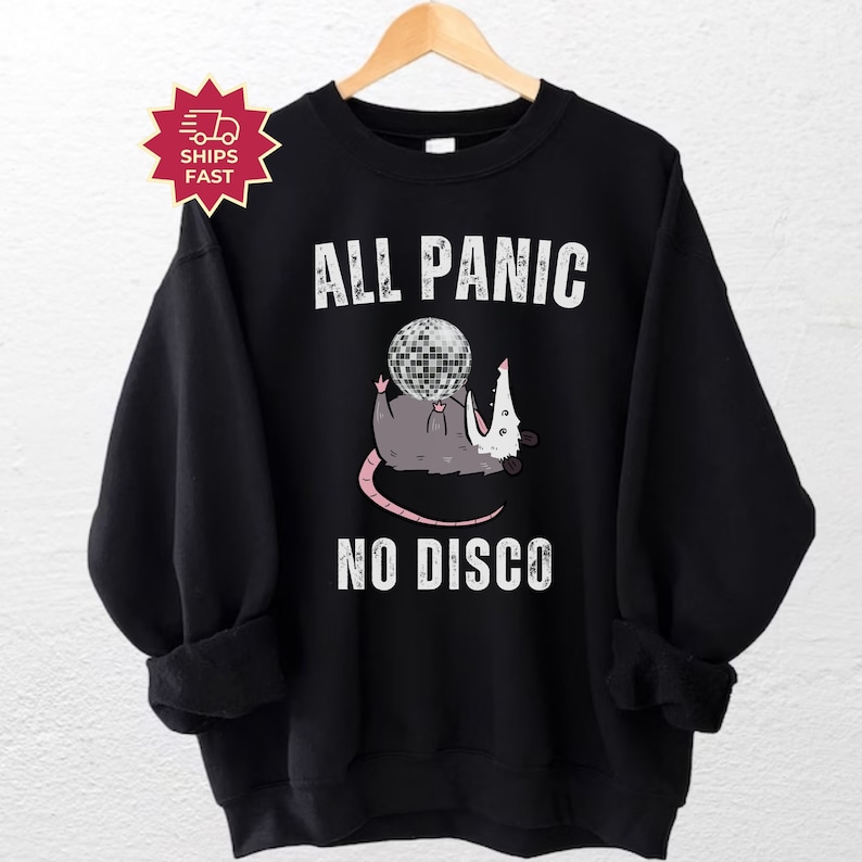 May include: Black sweatshirt with a white graphic of a possum holding a disco ball. The text "All Panic No Disco" is printed below the possum.