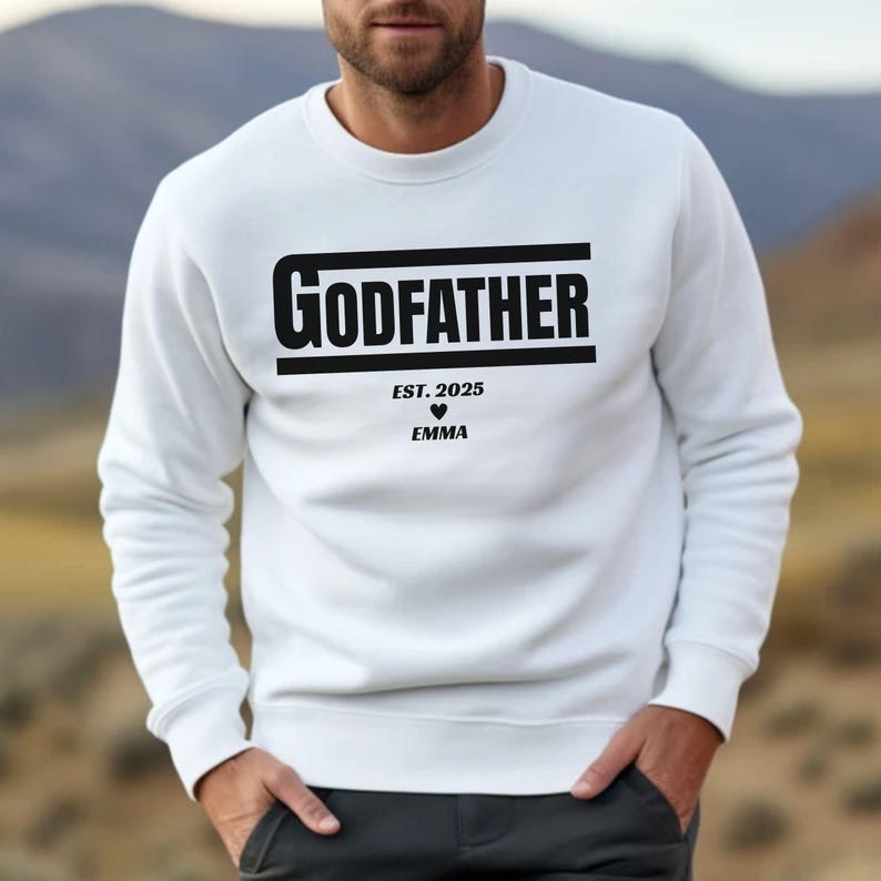 May include: White sweatshirt with black text that reads "GODFATHER EST. 2025" with a heart and the name "EMMA" underneath.