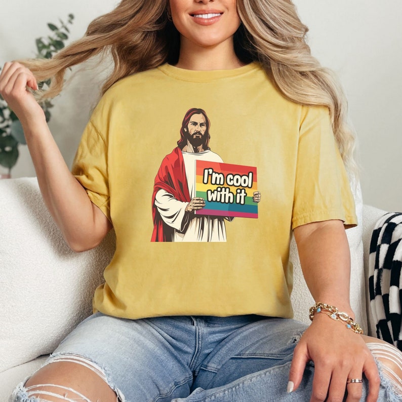 May include: A yellow t-shirt with a graphic of Jesus holding a sign that says "I'm cool with it". The sign has a rainbow stripe across the top.