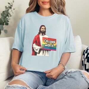 May include: A light blue t-shirt with a graphic of Jesus holding a rainbow flag that says "I'm cool with it".