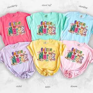 Może przedstawiać: Sześć kolorowych koszulek z napisem "Future Nurse" w żywym wzorze. Koszulki są w odcieniach różu, niebieskiego, zielonego, żółtego i fioletowego. Tekst jest ozdobiony sercami i zwierzęcym nadrukiem.
