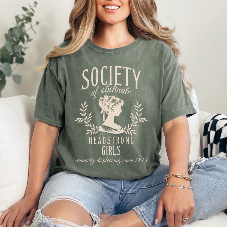 May include: A green t-shirt with the text "Society of obstinate Headstrong Girls seriously displeasing since 1813" and a vintage illustration of a woman.