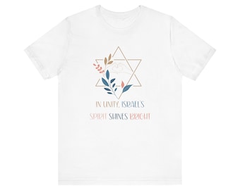 May include: White t-shirt featuring a Star of David design with floral accents and the text "IN UNITY, ISRAEL'S SPIRIT SHINES BRIGHT". The design includes a heart shape formed by hands.