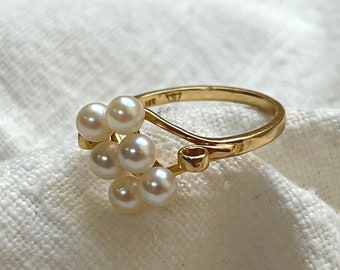May include: A gold ring with a cluster of white pearls set in a delicate, curved design.