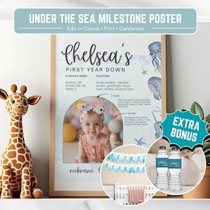 Puede incluir: Un póster de hitos con el texto "Under the Sea Milestone Poster" y "Chelsea's First Year Down". El póster incluye una foto, medidas y un peluche de jirafa. El póster está en un marco de madera.
