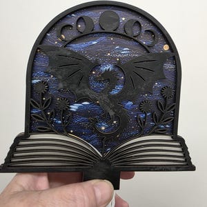 May include: A handmade wooden sign with the text "Welcome" in a playful font. The sign features a distressed white background and a dark brown border. A small, decorative heart is attached to the bottom.