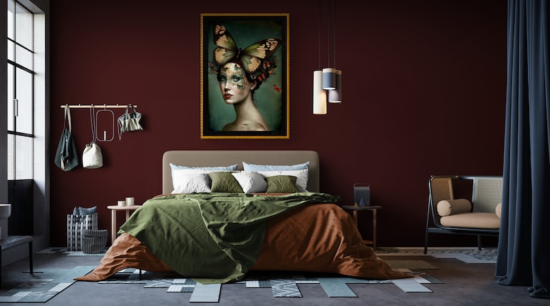 May include: A bedroom interior with a burgundy wall, a bed with green and brown bedding, a framed painting of a woman with butterflies on her head, and a chair with a cream cushion.