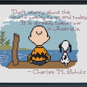 May include: Cross-stitch artwork featuring Charlie Brown and Snoopy with a quote: "Don't worry about the world coming to an end today. It is already tomorrow in Australia." The quote is attributed to Charles M. Schulz.