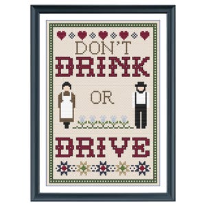 May include: Cross-stitch pattern with a framed image of a sign that reads "Don't Drink or Drive" with two figures in traditional clothing on either side of the text. The sign is decorated with hearts and flowers.