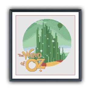May include: Cross stitch pattern of the Emerald City from the Wizard of Oz. The pattern features a green city with a yellow brick road leading to it. The text "The Wizard of Oz" is written in a yellow font.