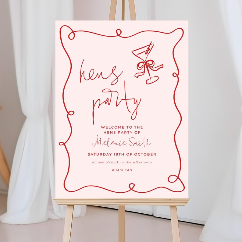 a pink sign with red cursive text and a graphic of a wine glass, welcoming guests to a hens party.
