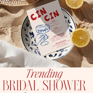 May include: A bridal shower invitation with the words "CIN CIN" in red, a blue cocktail illustration, and event details. The invitation is on a plate with lemons and a white cloth.