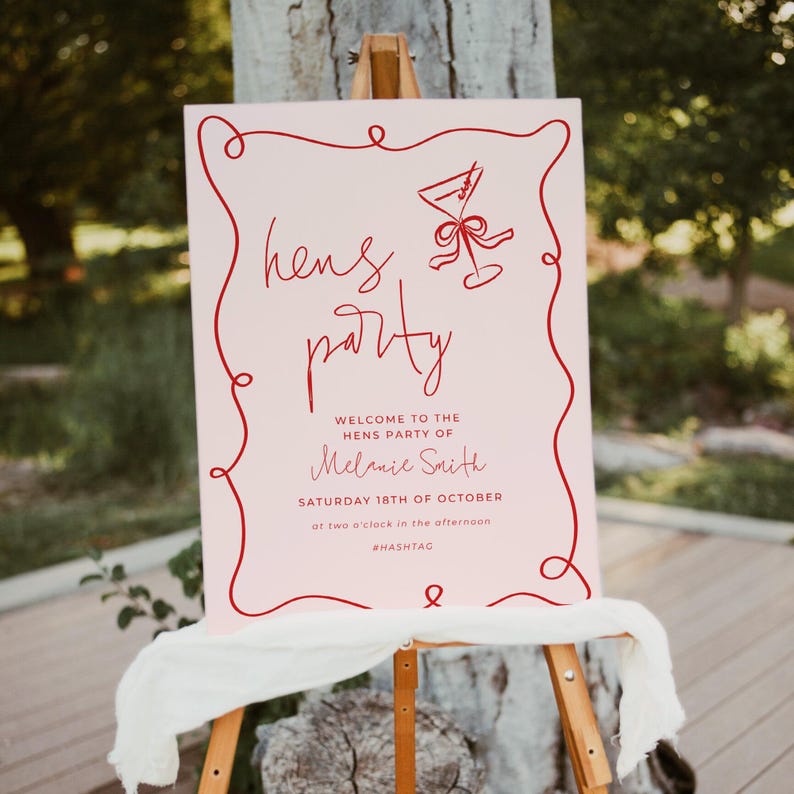 a pink sign with red text and a graphic design, placed on a wooden stand in front of a tree.