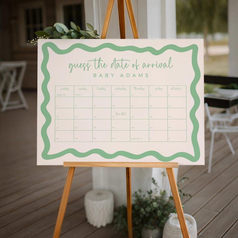 a guessing game board for the date of arrival of a baby named Adams. The board is set up on a wooden easel, with a potted plant and a chair visible in the background.